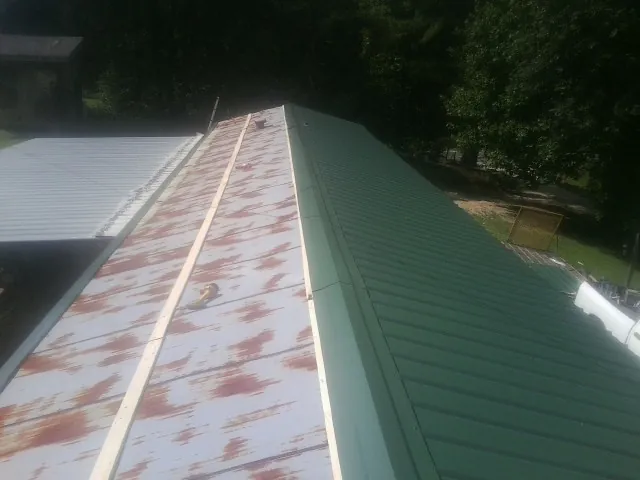 Old rusted panels beside newly installed green metal roofing — Wind Damage Roof Repair by Roofing Brothers in Falls Of Rough