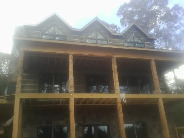 Dormers and porch framing on a large log home under construction — Roof Coating work by our crew in Falls Of Rough