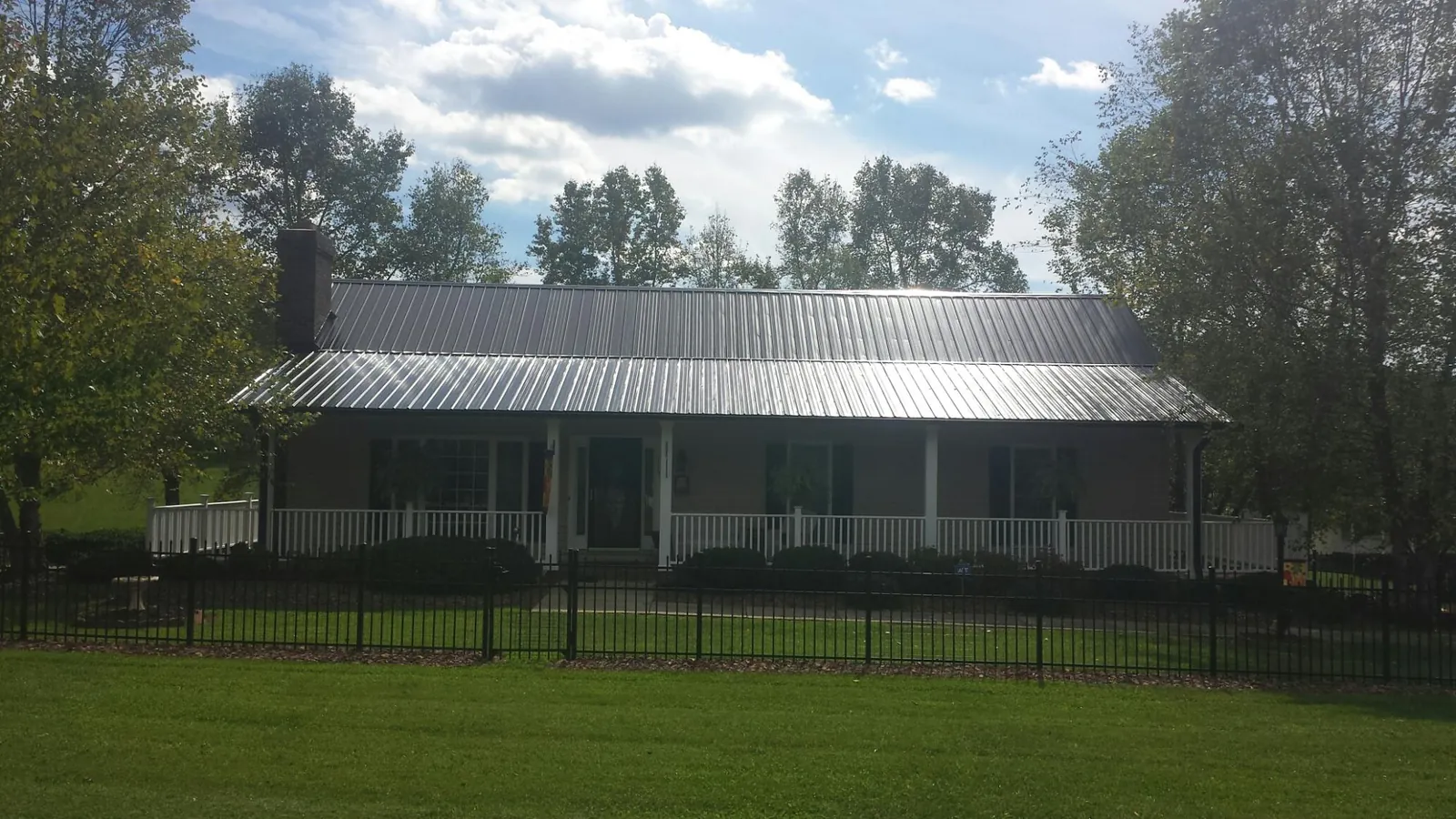 Gray metal roof on a brick ranch with a full width front porch — Gutter Guard Installation work by our crew in Falls Of Rough