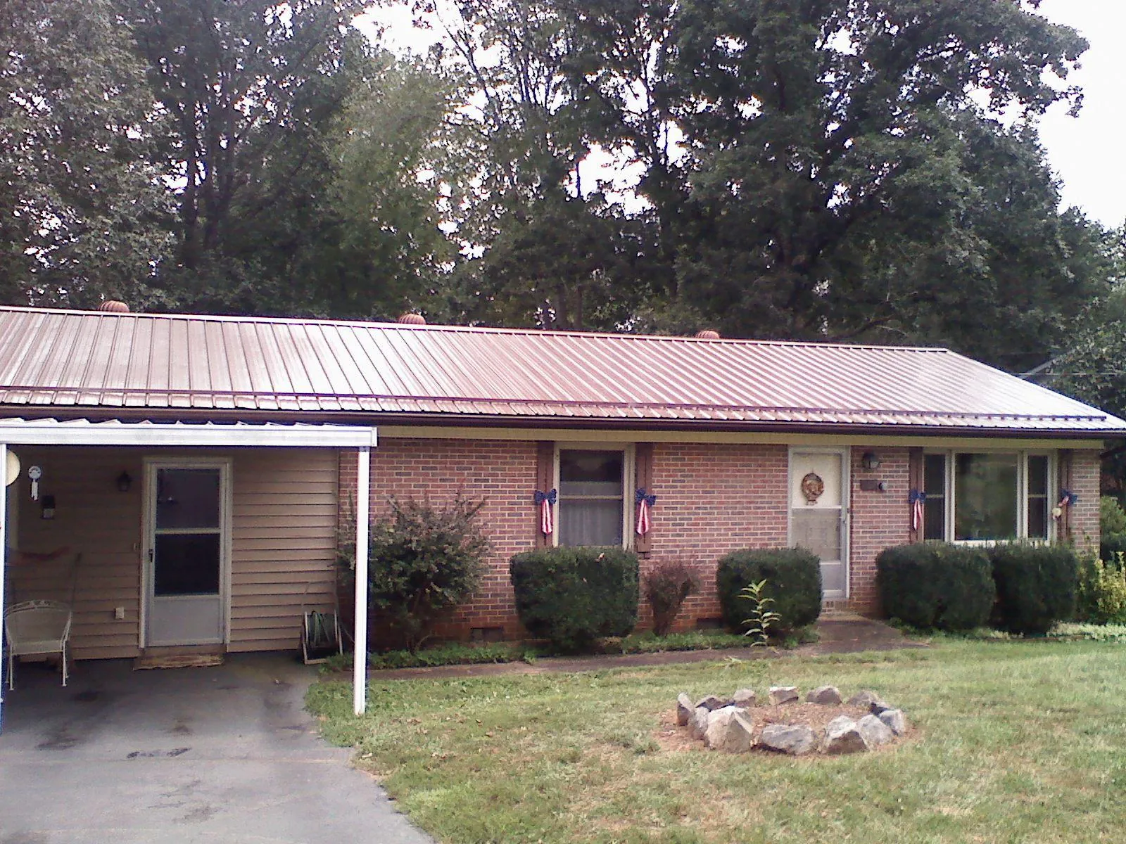 Bronze metal roof and carport on a brick ranch home — Roof Repair work by our crew in Falls Of Rough