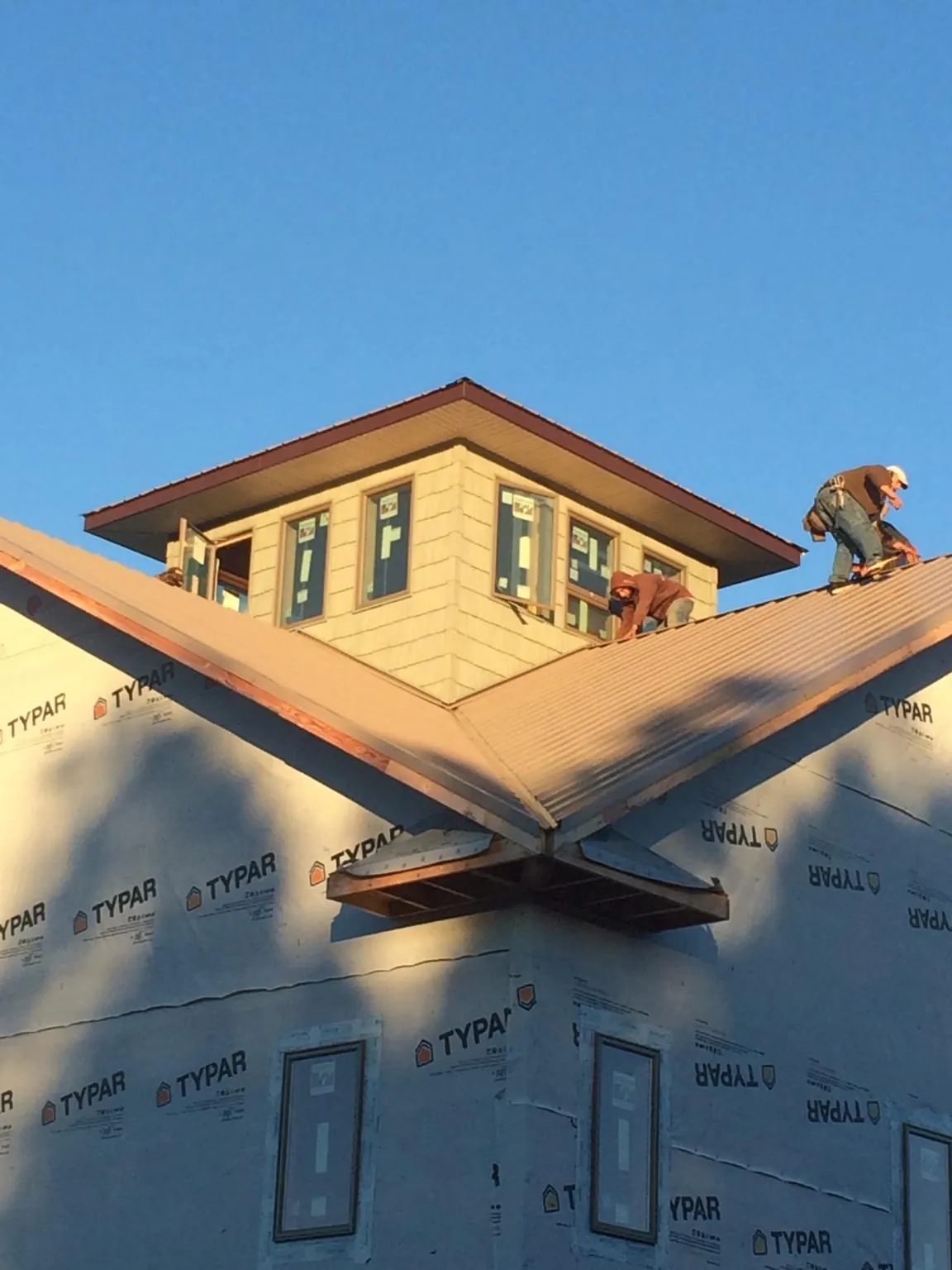 Roofers working around a rooftop cupola on a new metal roof at sunset — Roof Waterproofing in Falls Of Rough by Roofing Brothers